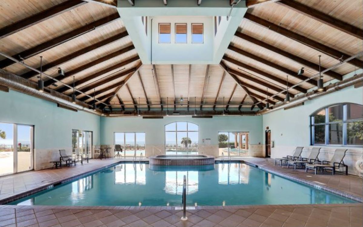 A swimming pool with a wooden ceiling and large windows.