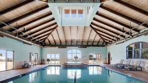 A swimming pool with a wooden ceiling and large windows.