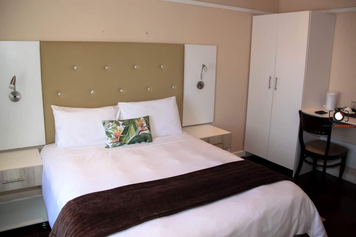 Una habitación de hotel con una cama grande, un escritorio con una silla y un armario.