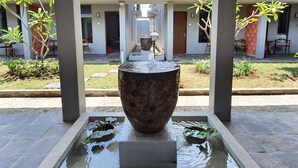 A courtyard with a central water feature, surrounded by a covered walkway and potted plants.