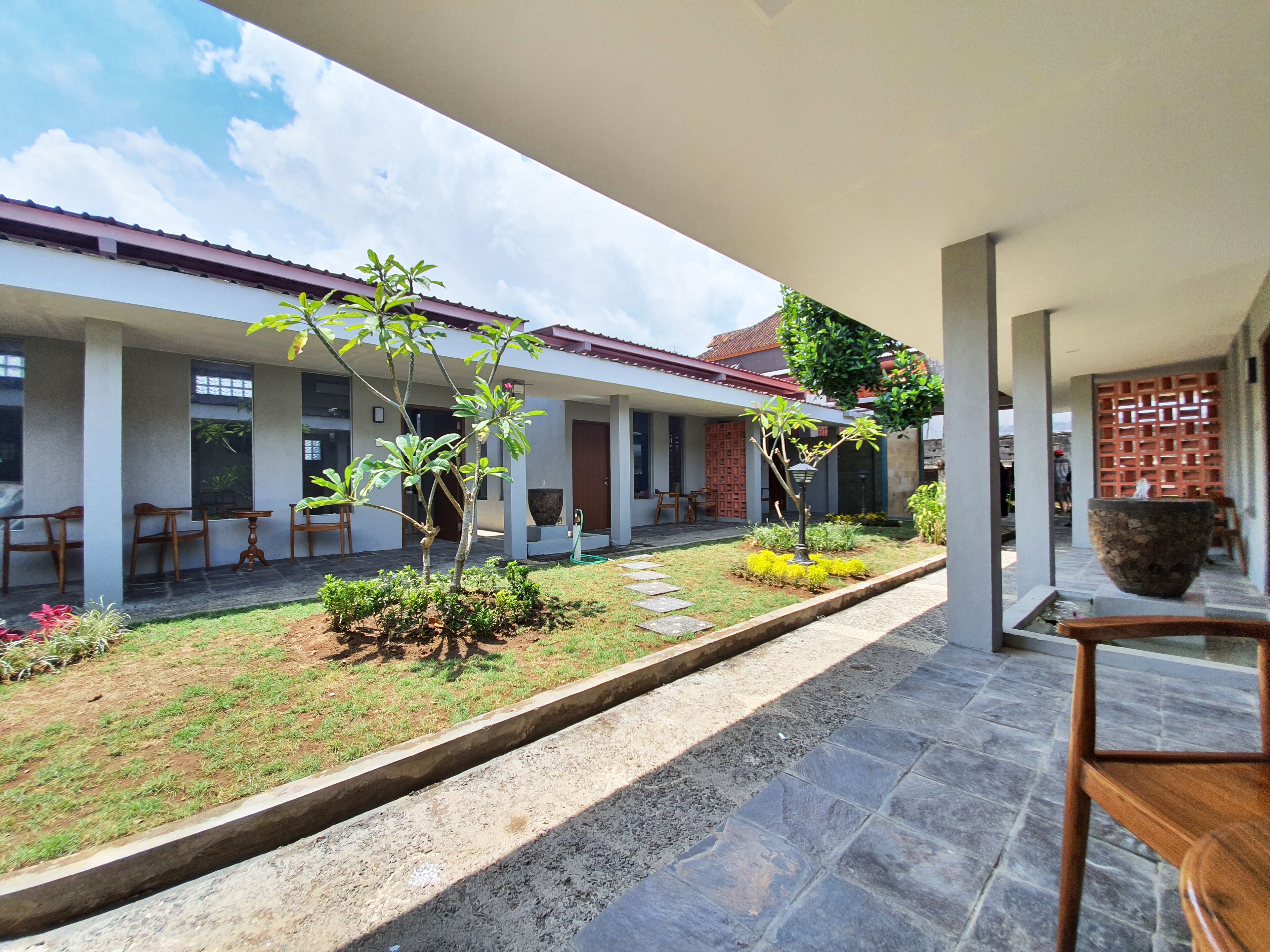 A courtyard with a tiled floor, a few potted plants, and outdoor seating.