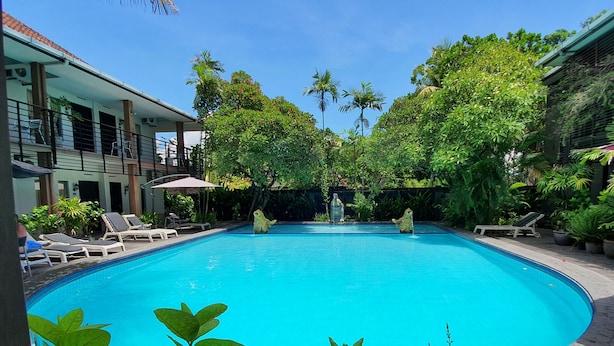 A swimming pool with lounge chairs and tropical plants.