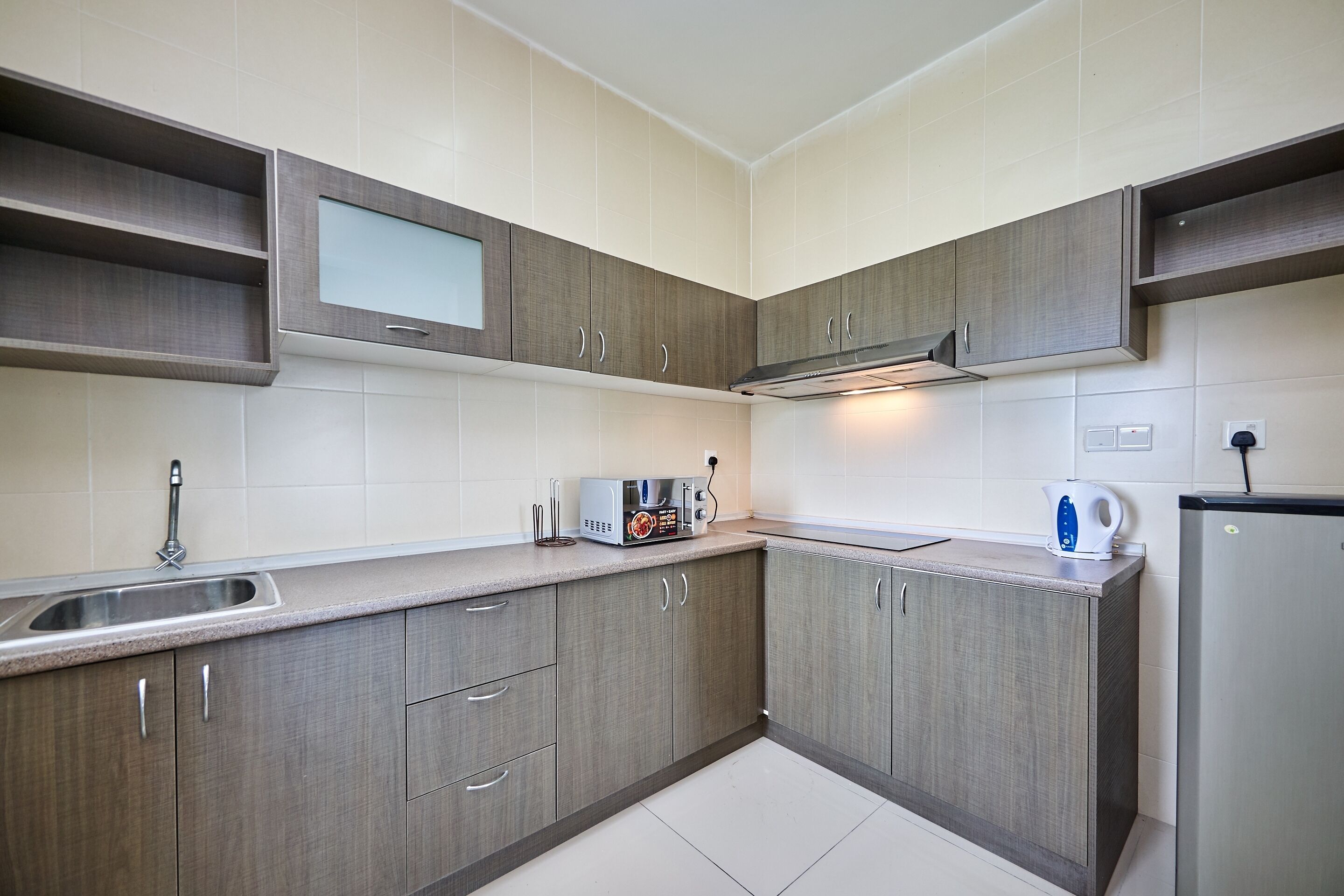 A modern kitchen with grey cabinetry, a stainless steel sink, and a built-in microwave.