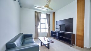 A modern living room with a sofa, a coffee table, a TV, and a ceiling fan. - OYO Home 89748 Classic 3 Br The Arc (Cyberjaya)