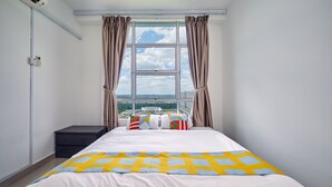 A hotel room with a large bed, a window with curtains, a bedside table, and a view of the cityscape. - OYO Home 89748 Classic 3 Br The Arc (Cyberjaya)