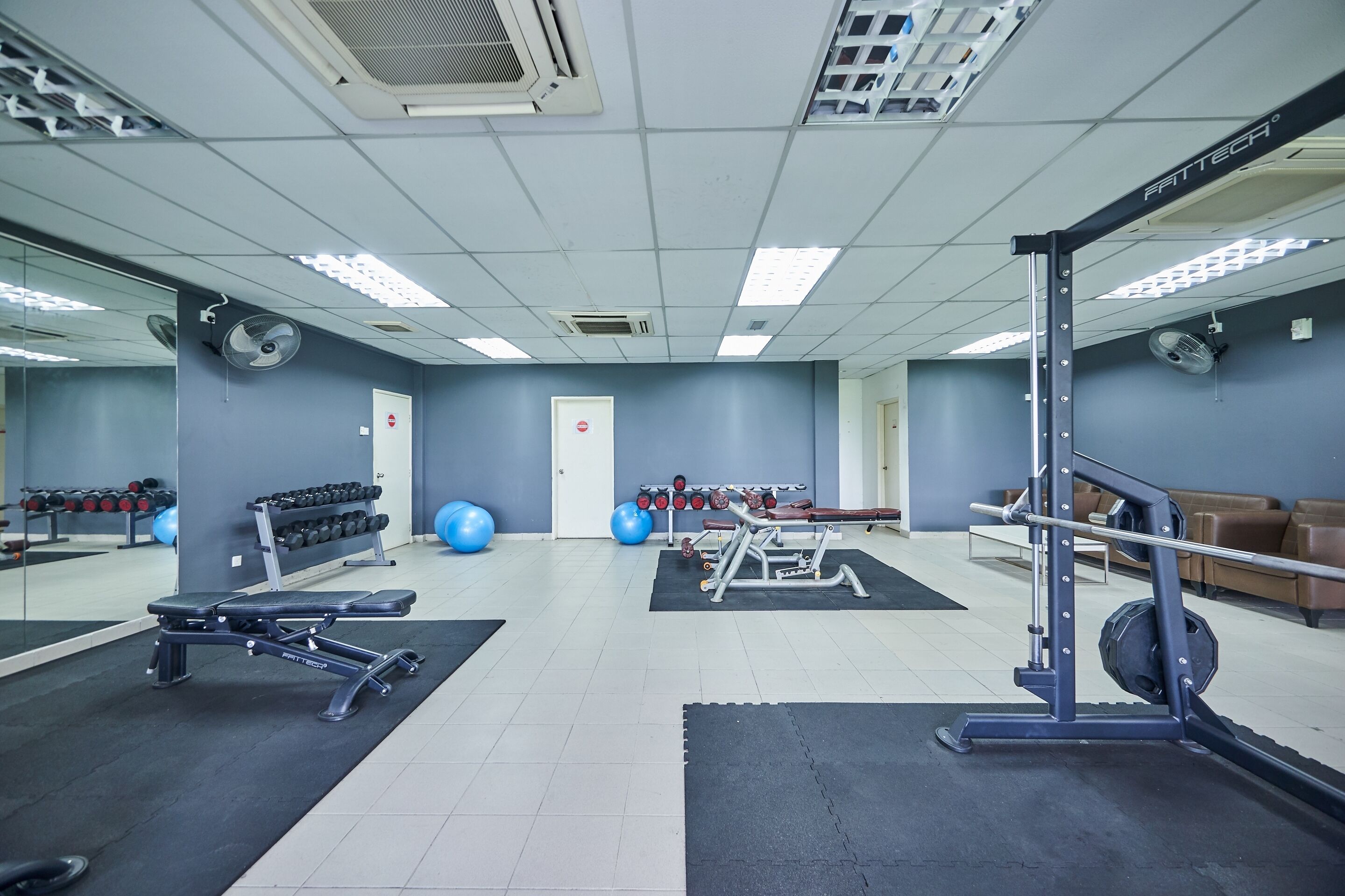 A gym with exercise equipment, mirrors, and a weight rack.