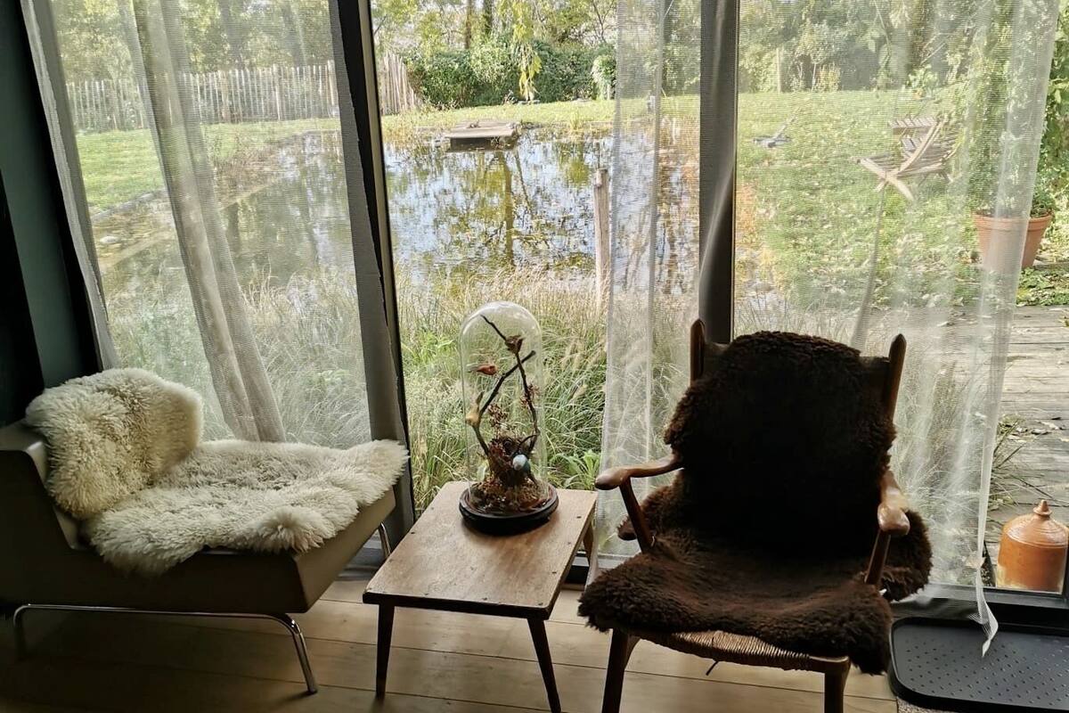 A room with a large window, a chair, a small table, and a decorative item.