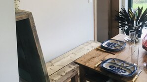A dining area with a wooden table, a framed picture on the wall, and a potted plant. - Panacée Guesthouses (Ronse)