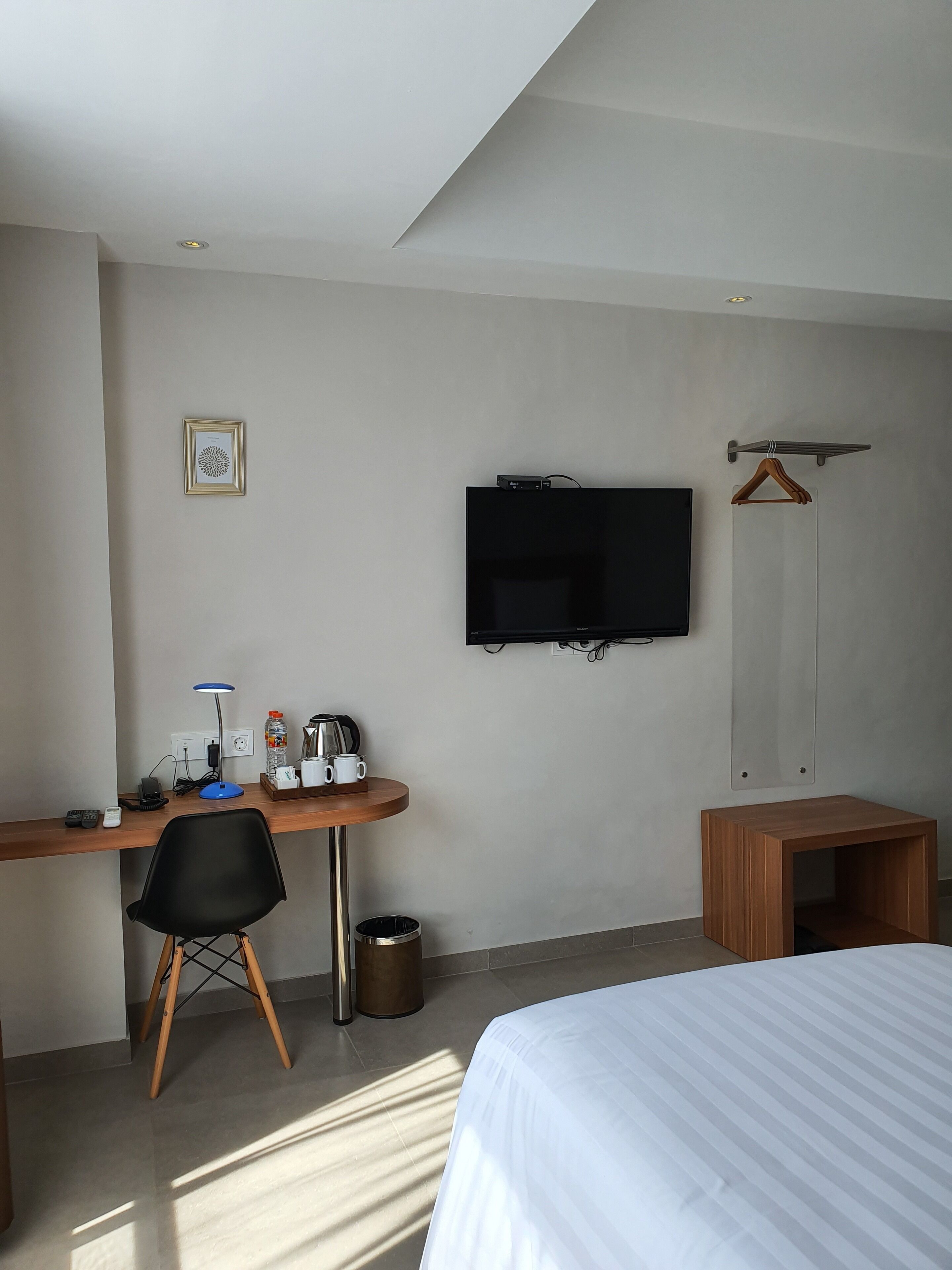 Ein Hotelzimmer mit einem Bett, einem Schreibtisch mit Stuhl, einem Fernseher und einem kleinen Holzschrank.