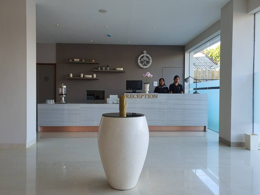 Een moderne receptiebalie met een groot aanmeldingsscherm, een decoratief kunstwerk en een grote vaas op de voorgrond.