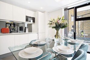 Enjoy meals in a stylish dining area with a glass table, vase, and elegant flowers.