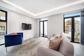 Relax in this stylish living room with a large flat-screen TV, glass coffee table, and comfortable sofas.