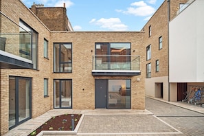 Stylish urban building with a central entrance, glass door, and a small garden area.