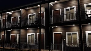 Un immeuble à plusieurs étages doté de balcons et d’un éclairage extérieur.