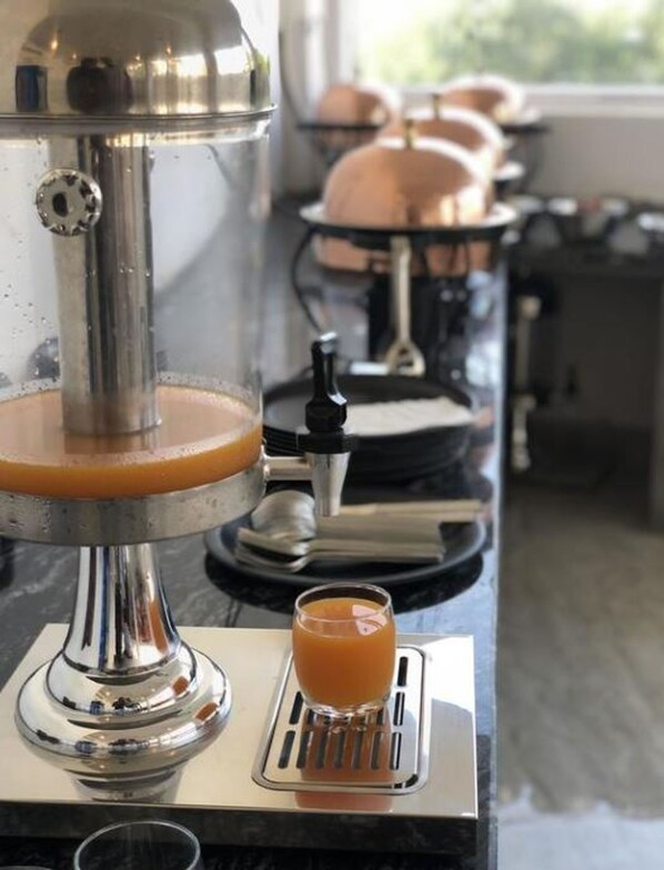 A coffee machine with a glass of orange juice on a tray.