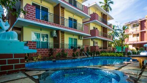 Un hotel con piscina, varios balcones y fachada de ladrillo.