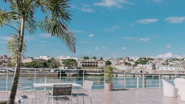 En takterrass med sittplatser, med utsikt över en vattenyta och en stadsbild.