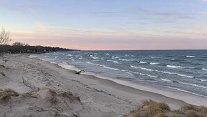 En strand med bølger, et hegn og en klar himmel.