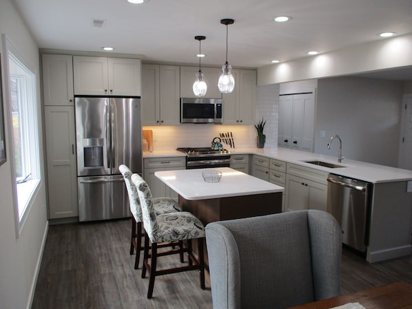 A modern kitchen with stainless steel appliances, a central island, and pendant lighting.