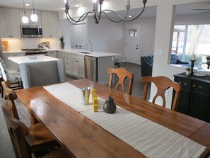 A modern kitchen with white cabinets, a stainless steel microwave, and a dining area with a wooden table and chairs.