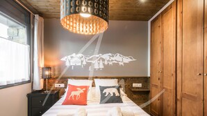 A hotel room with a bed, a wooden wardrobe, a nightstand, a lamp, and a wall projection of a mountain scene. - Beroia (Vielha e Mijaran)