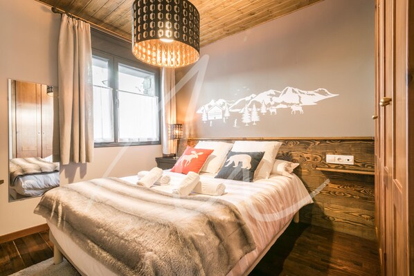 Un dormitorio con cama, ventana, espejo, cabecera de madera y una proyección en la pared.