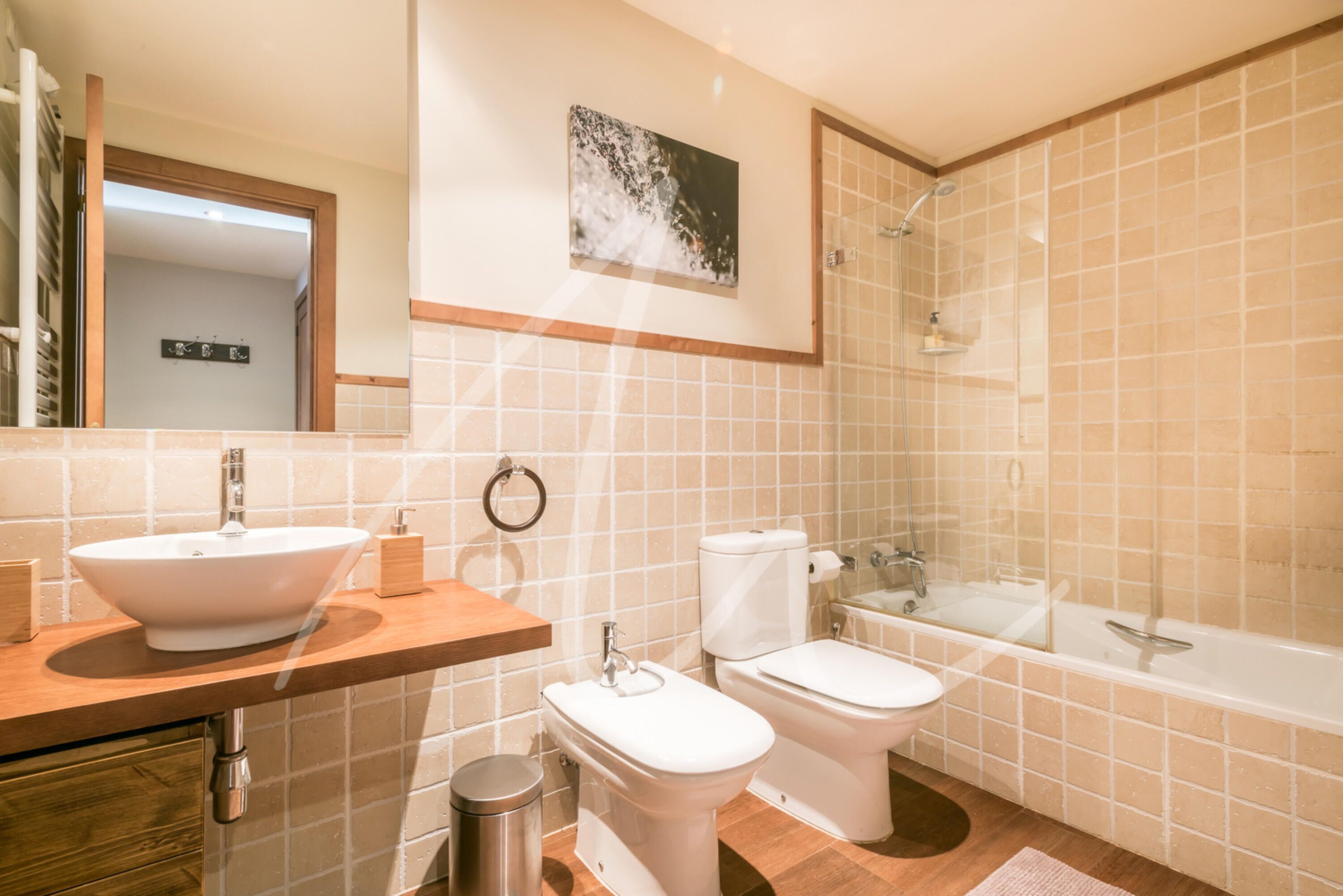 A modern bathroom with a sink, toilet, bidet, and bathtub.
