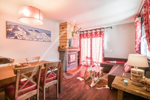 Una sala de estar acogedora con chimenea, muebles de madera y un cuadro de montañas en la pared.