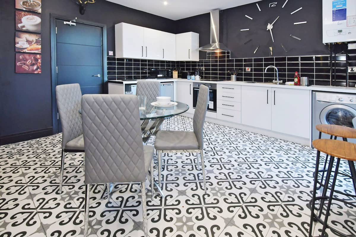 A modern kitchen with white cabinets, a black backsplash, and a patterned floor.