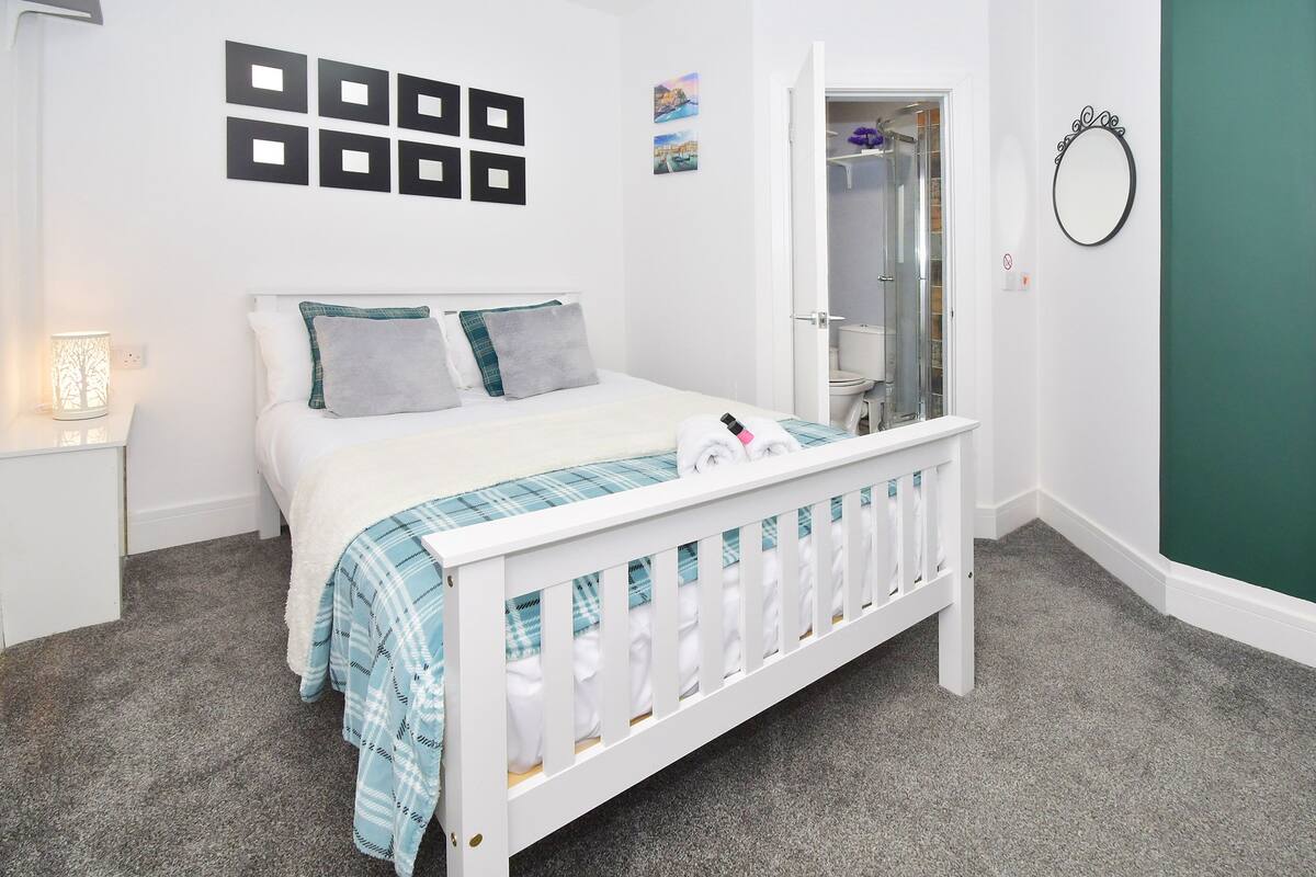 A neatly arranged bedroom with a bed, bedside table, and a mirror on the wall.