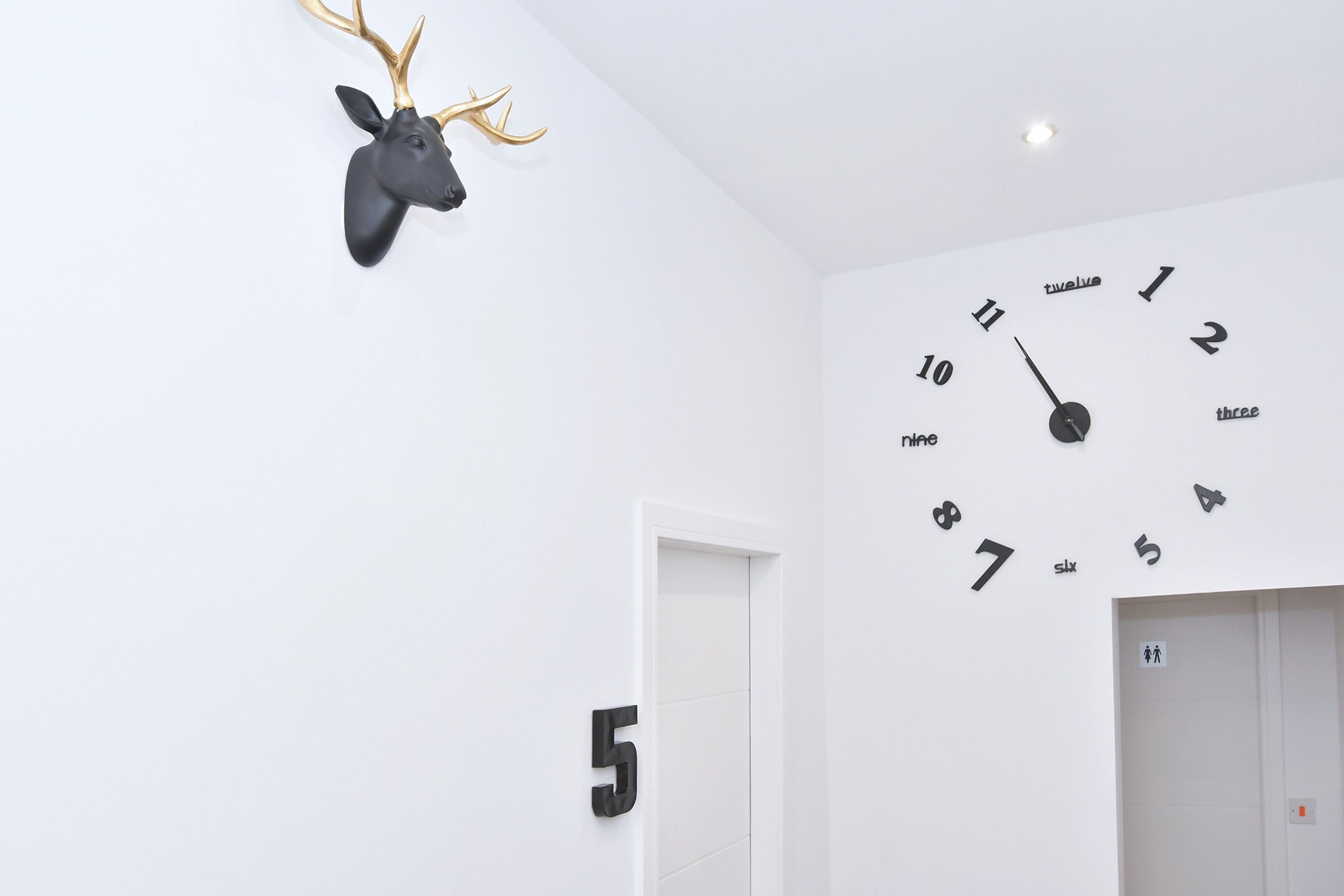 A room with a wall clock, a mounted deer head, and a door labeled '5'.