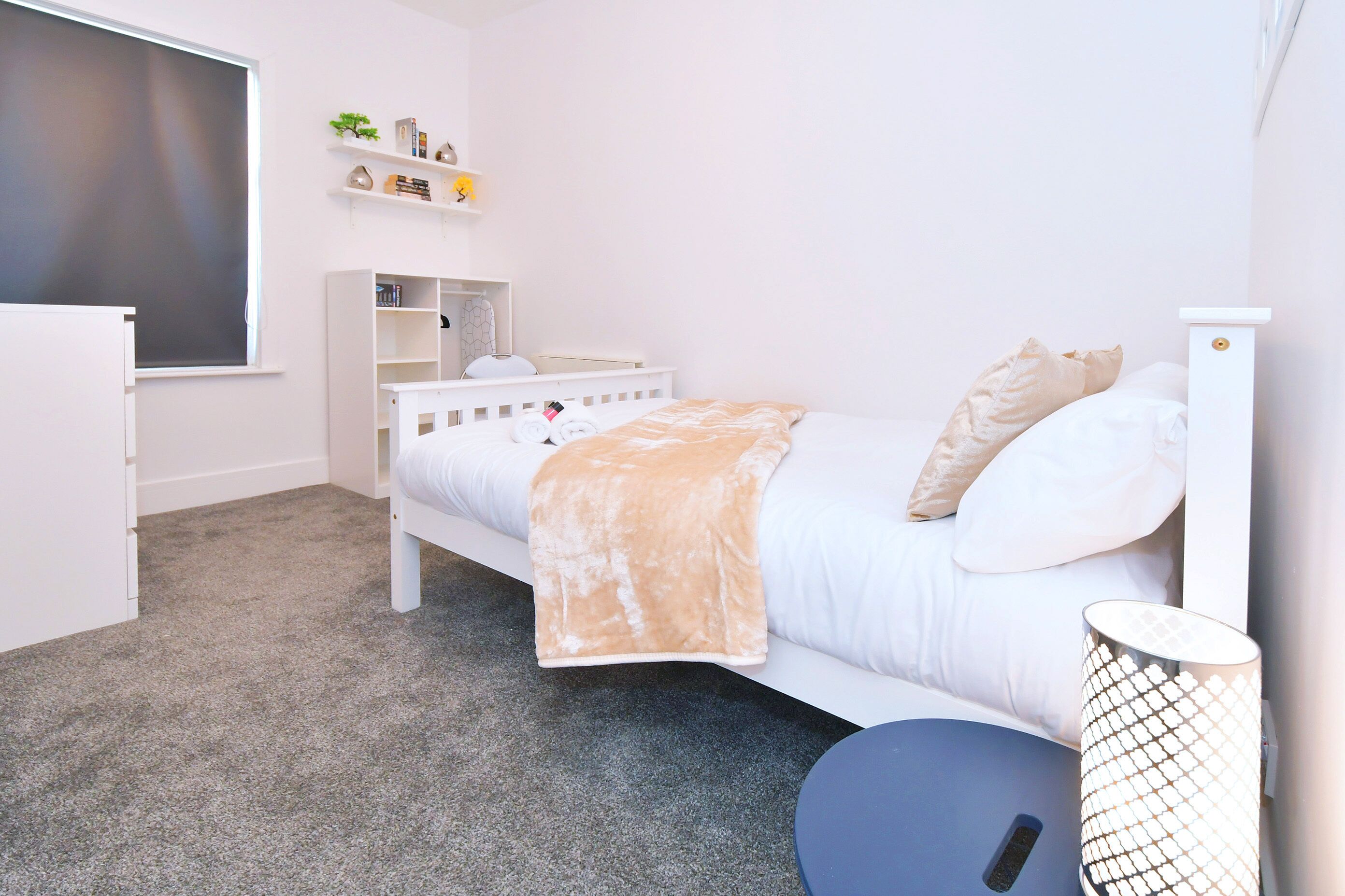 A bedroom with a bed, a desk, a chair, a bookshelf, and a window.