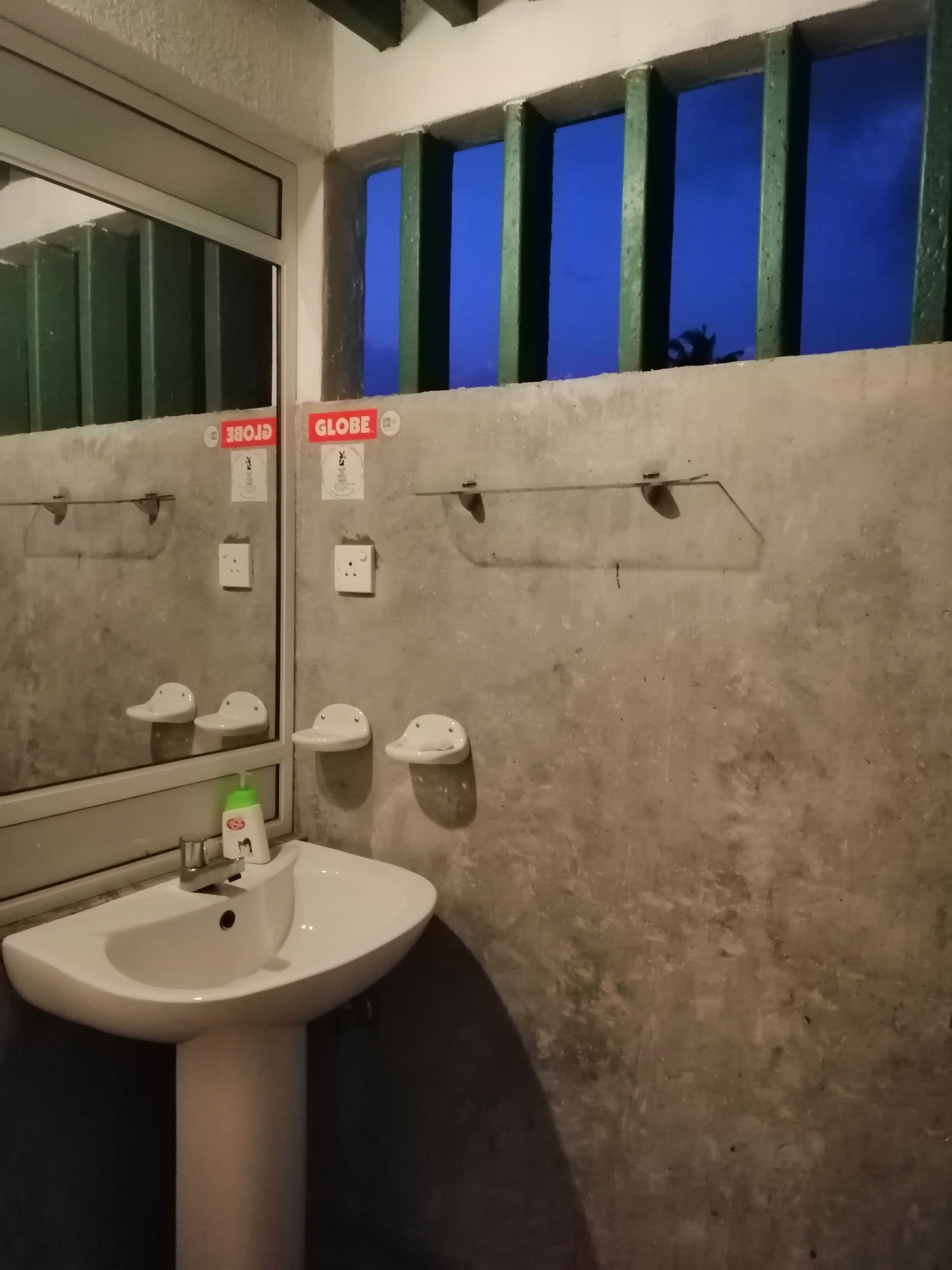 Un baño con lavamanos, espejo y toalleros.