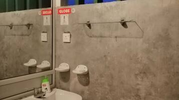 Un baño con lavamanos, espejo y toalleros.