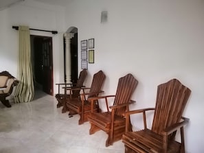 A room with wooden chairs arranged in a row, a white pillar, and a door with a curtain.