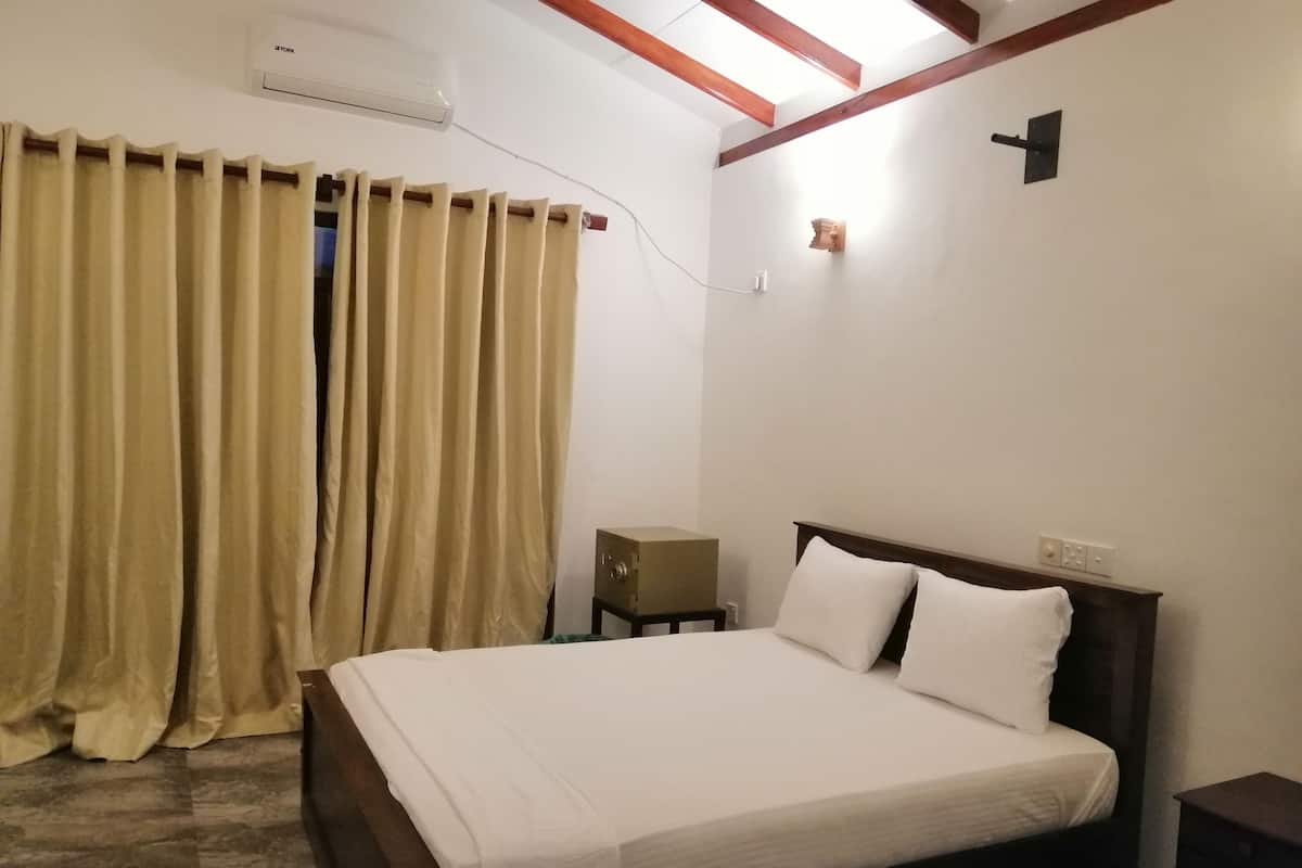 Quarto com cama, cortinas, mesa de cabeceira e luminária fixa na parede.