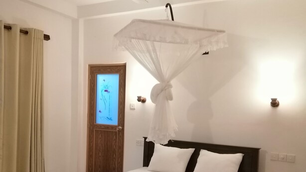 Une chambre à coucher comprenant un lit, un ventilateur de plafond, une porte et un luminaire fixé au mur.