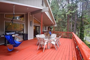 A covered outdoor deck with a grill, dining table, and chairs.