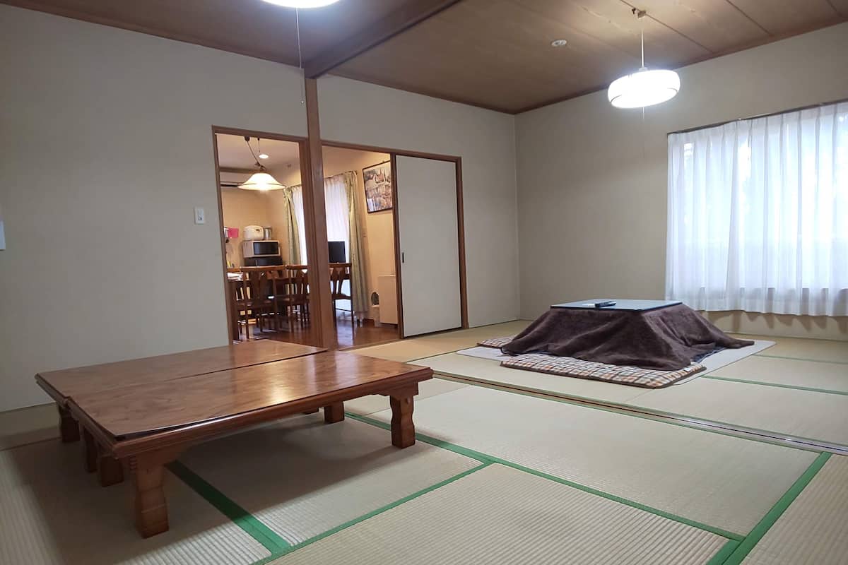 A traditional Japanese room with tatami flooring, a low wooden table, and a futon bed.