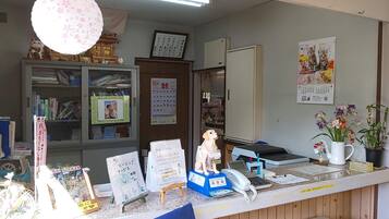 A reception desk with a 'FRONT' sign, a calendar, a phone, and various informational posters.