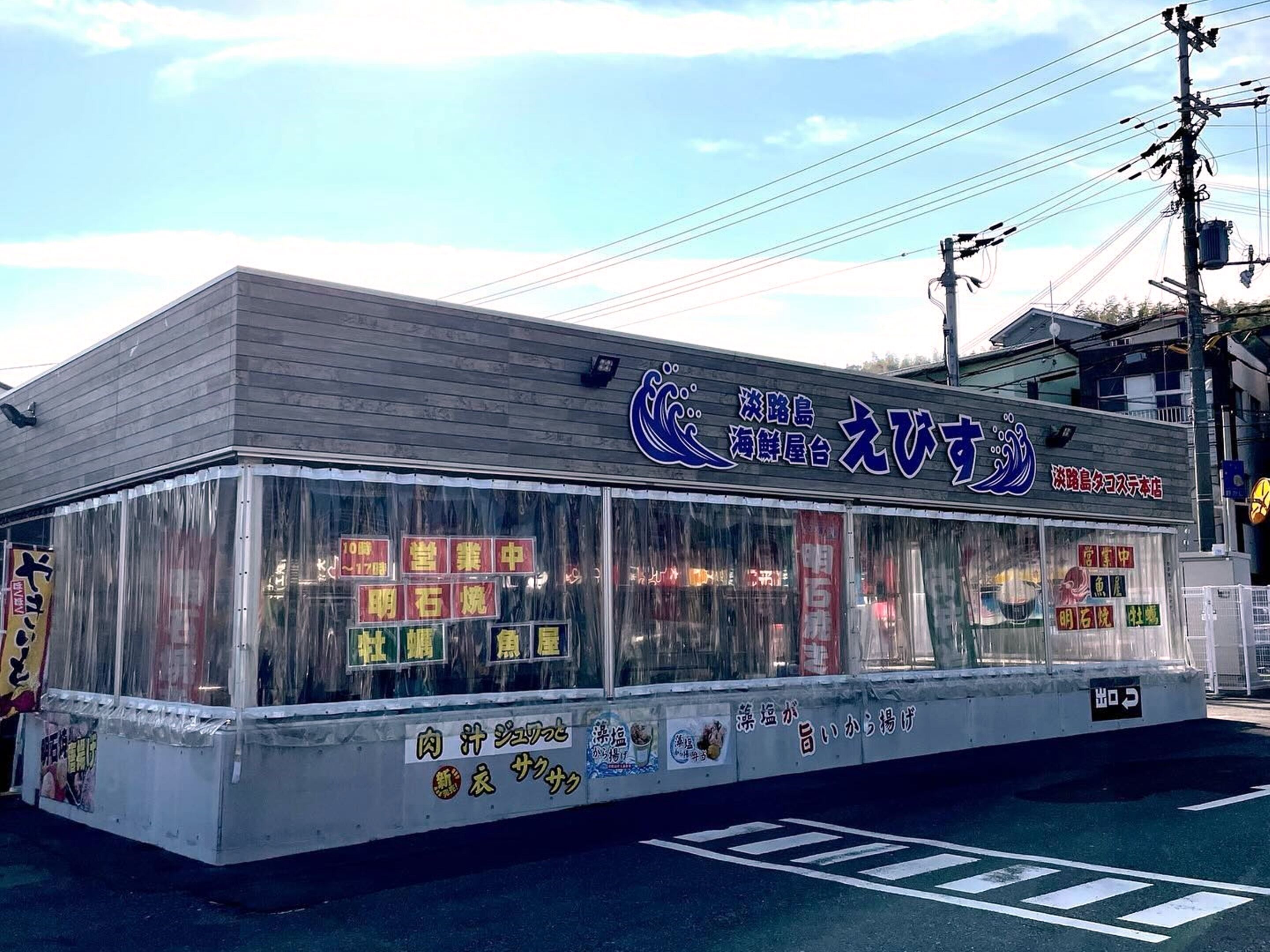 A restaurant with a clear glass front, displaying various food items and a sign with Japanese characters.