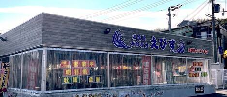 A restaurant with a clear glass front, displaying various food items and a sign with Japanese characters.