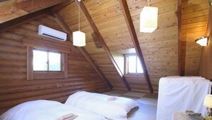 Una habitació d'alta cabana acollidora amb dos llits, una taula petita i una finestra.