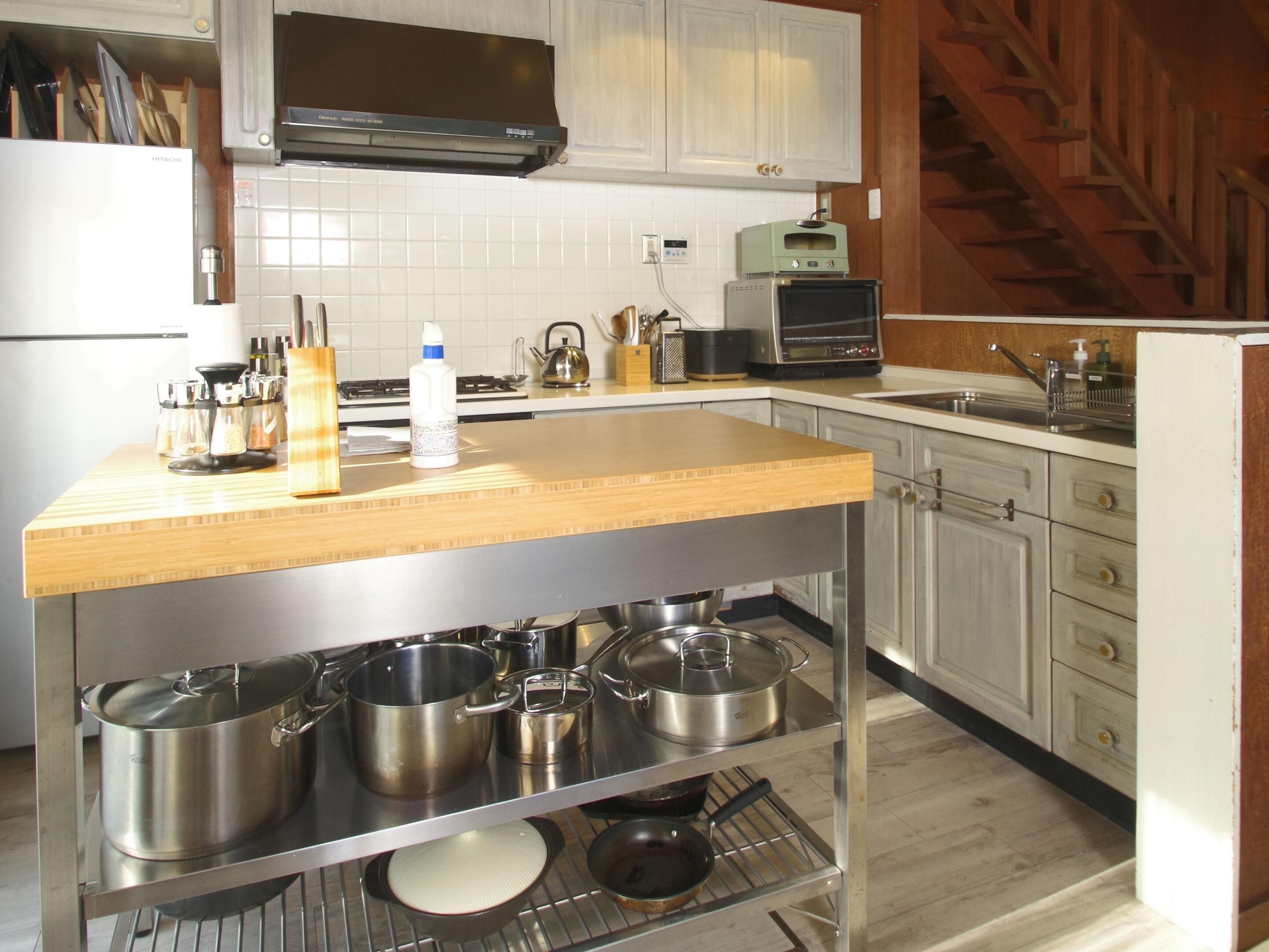 A kitchen with a wooden countertop, stainless steel pots, a microwave, and a stove.