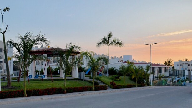 A resort with a pool area, palm trees, and a clear sky.