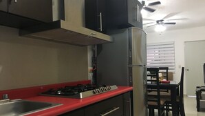 A kitchen with a red countertop, stainless steel appliances, and a ceiling fan.