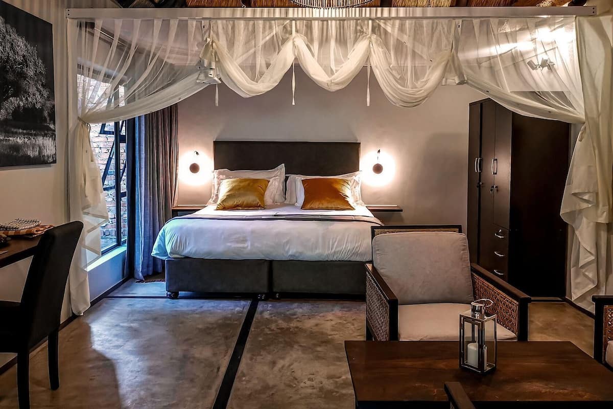 A bedroom with a large bed, bedside tables, a wardrobe, and a view of the outdoors.