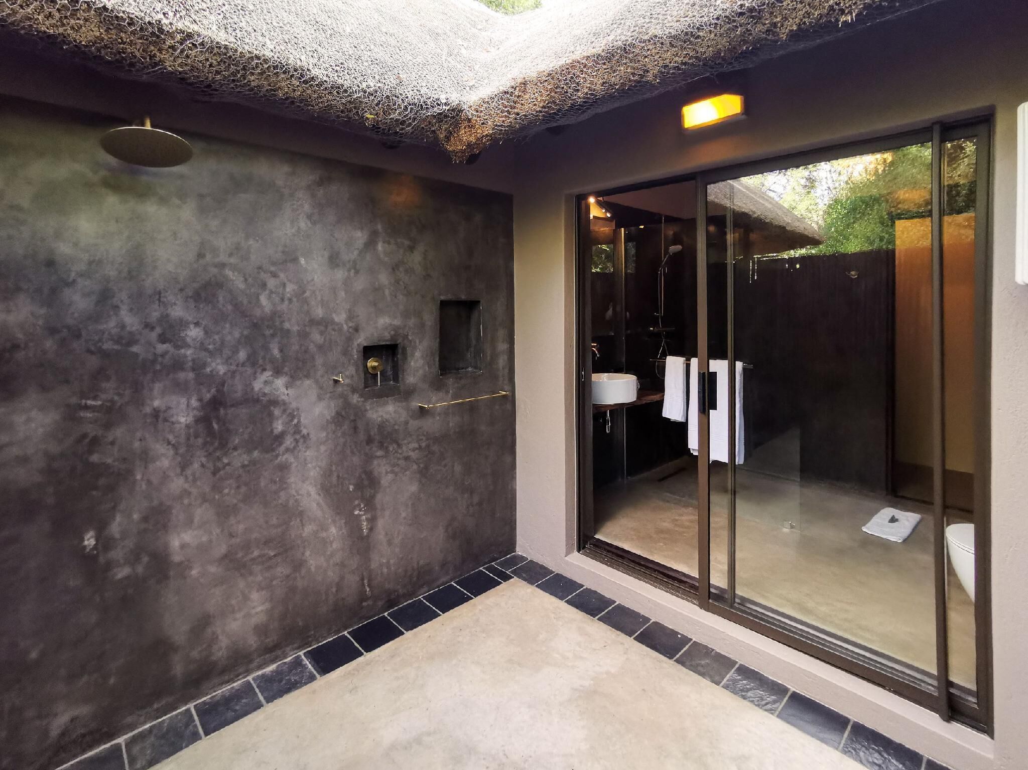 A modern bathroom with a large glass shower enclosure, a built-in sink, and a textured wall.