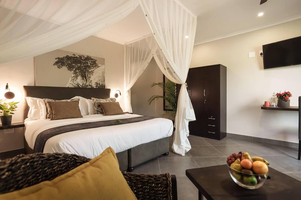 A modern bedroom with a bed, bedside tables, a fruit bowl, a TV, and a wardrobe.
