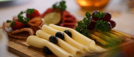 Una tabla de madera con varios quesos, uvas y hierbas.